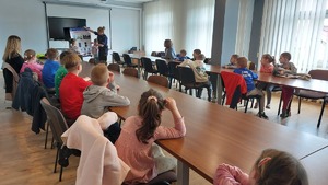 spotkanie policjantów z dziećmi z przedszkola nr 13 z Przemyśla. Dzieci siedzą przy stołach na auli i słuchają prelekcji.