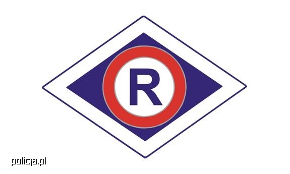 Znak oznaczający wydział ruchu drogowego. Duża litera R w granatowym kolorze umieszczona w rombie w kolorze granatowo czerwonym na białym tle