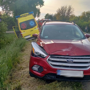 samochód ford w kolorze czerwonym stojący na poboczu , widoczny uszkodzony prawy przedni zderzak i lampa