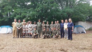 zdjęcie grupowe harcerzy , policjantek, strażaków i pracownika sanepidu na placu namiotowym