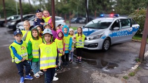 zdjęcie grupowe przedszkolaków z policjantką przy radiowozie policyjnym