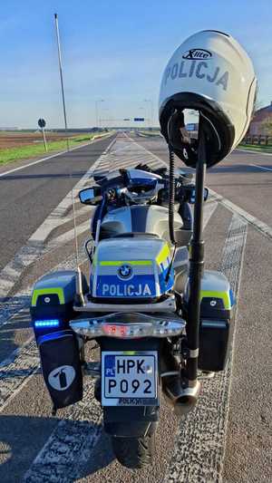 Zdjęcie kolorowe przedstawia jeden motocykl policyjny stojący na jezdni