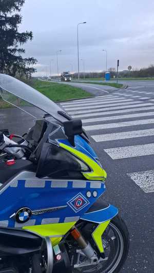 Zdjęcie kolorowe przedstawia jeden motocykl policyjny stojący na jezdni