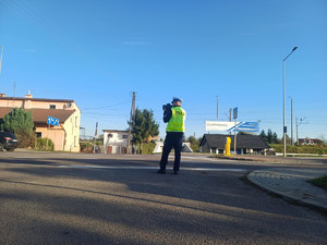 umundurowany policjant z miernikiem prędkości ustawiony przy drodze w trakcie działań