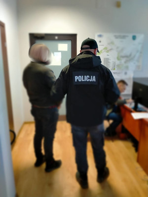 Policjant w pomieszczeniu z osobą zatrzymaną - mężczyzną