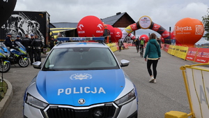 radiowóz policyjny, a w tle meta i start &quot;Orlen Lang Team Race&quot; i &quot;Orlen Wyścig Narodów&quot;