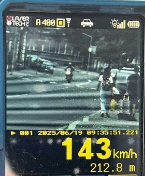 zdjęcie z wideo rejestratora, na którym znajduje się   pomiar prędkości oraz  poruszający się po drodze  motocyklista. Wskazana jest również data i gadzina wykonanego pomiaru.